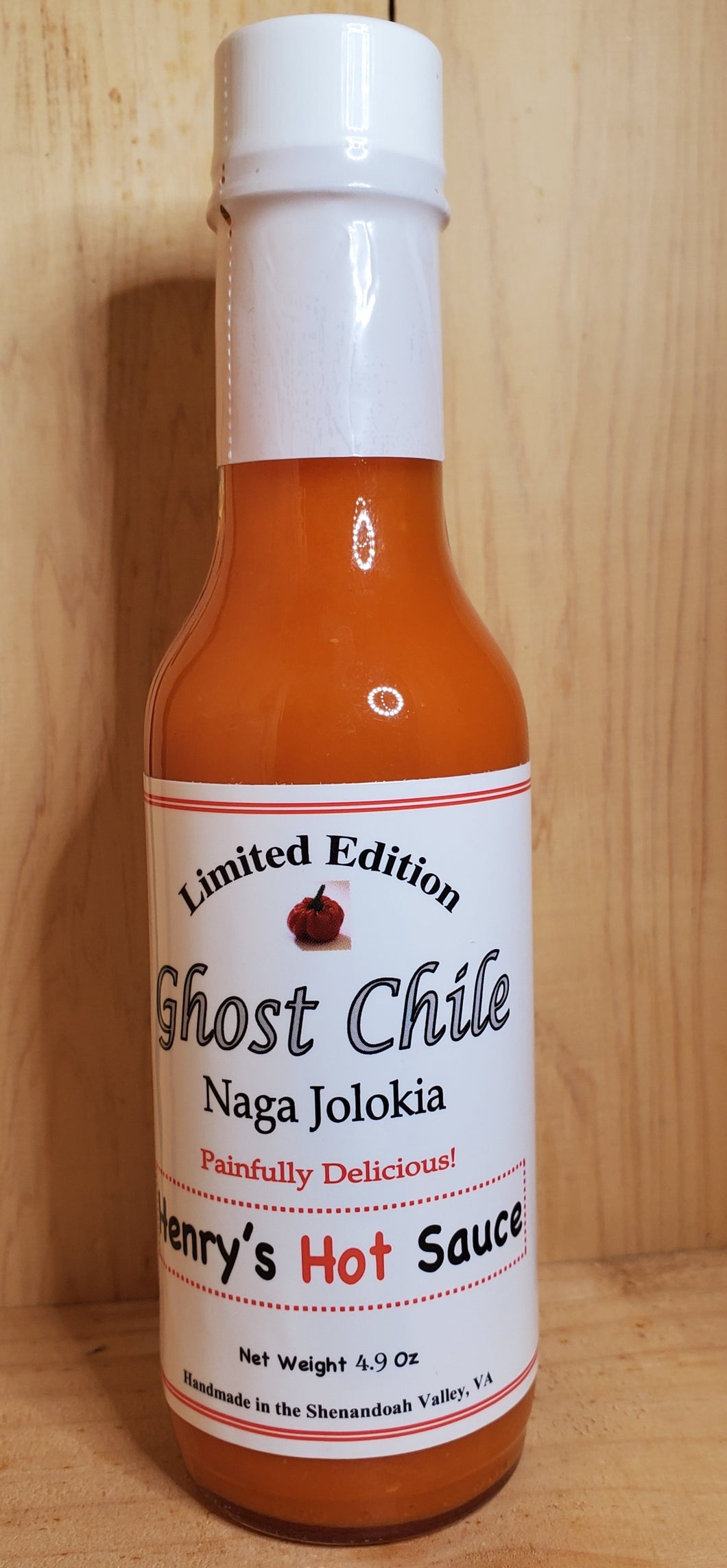 large glass bottle at 5 oz o hot sauce with red ghost chile in it