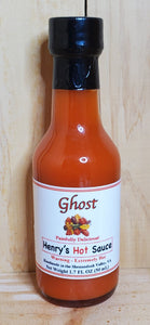 small glass bottle with red hot sauce in it of ghost pepper sauce