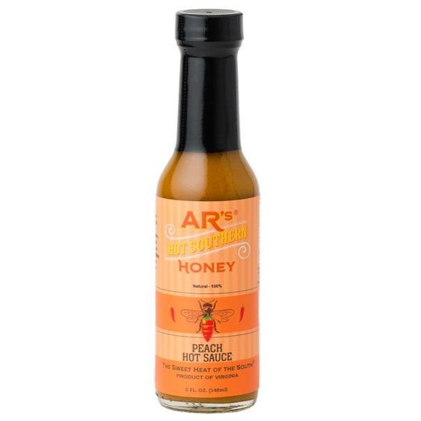 glass bottle with a orange label and a bee saying peach hot sauce with tumeric