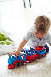 a small boy playing with a train set